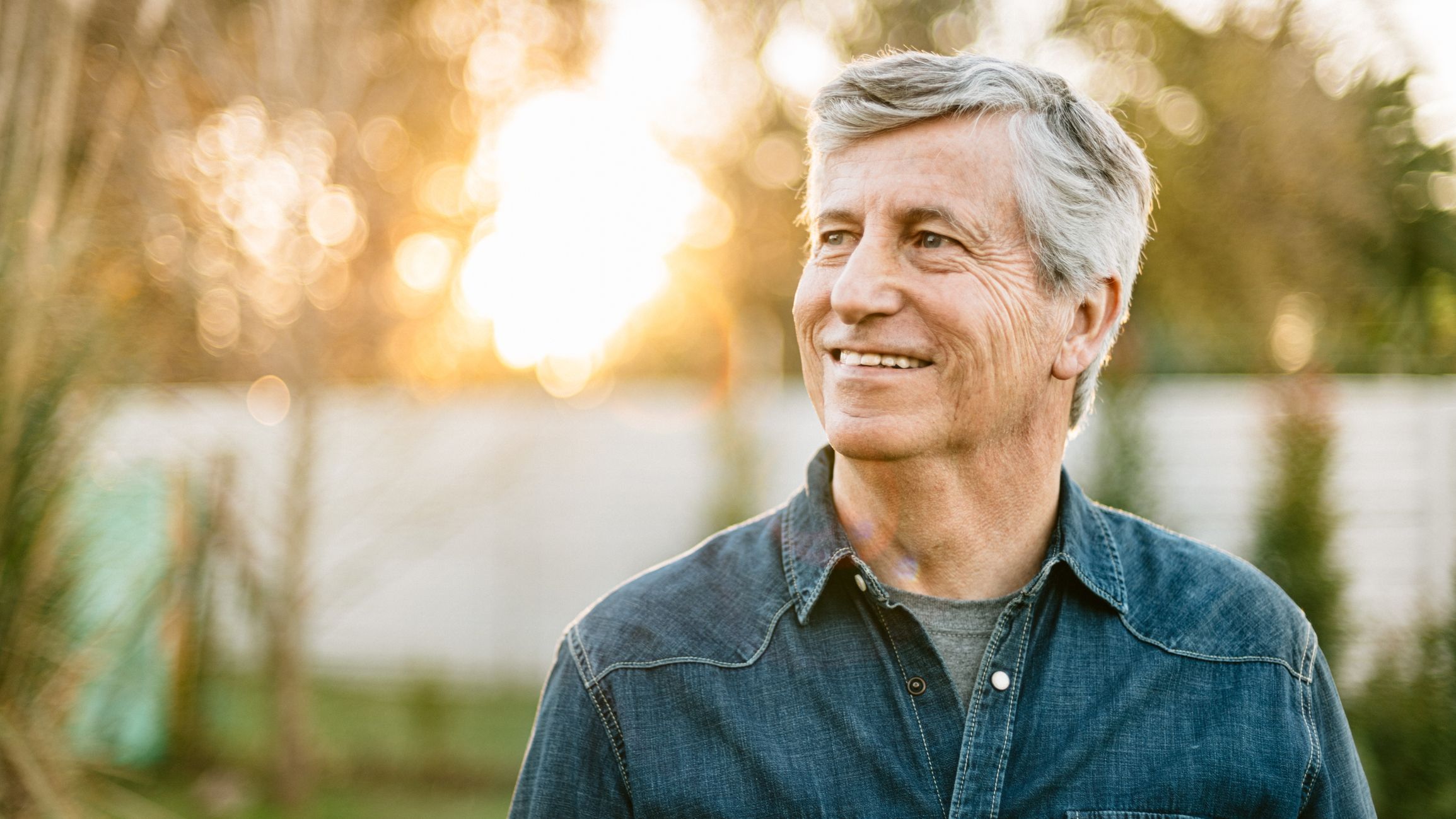 A 62-year-old man approaching retirement smiles as he thinks about his future. 